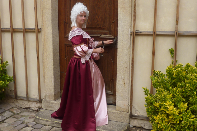 Komtesa s rokokovou parukou se chystá otevřít dveře velikým klíčem.